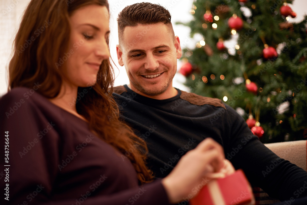 Gift, christmas and couple relax together for holiday festive celebration. Happy, smile and surprise present box to celebrate xmas, love and happiness on sofa in living room with christmas tree