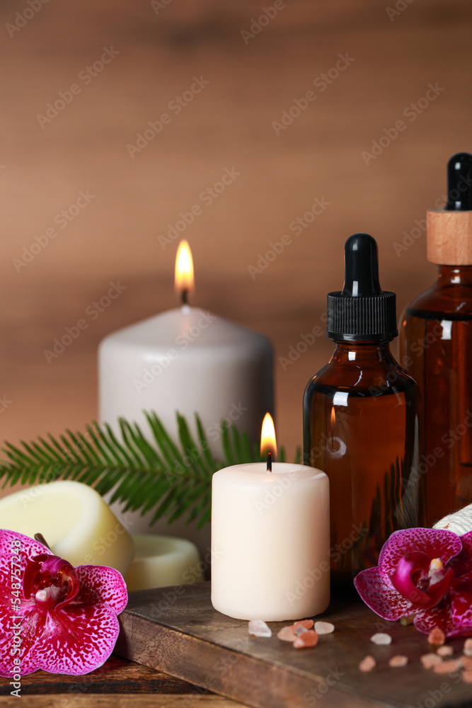 Beautiful spa composition with different care products and burning candles on wooden table Beautiful spa composition with different care products and burning candles on wooden table