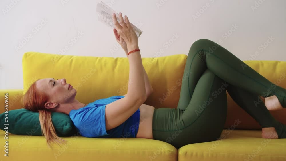 Adult woman lying on the couch and reading book Adult woman lying on the couch and reading book