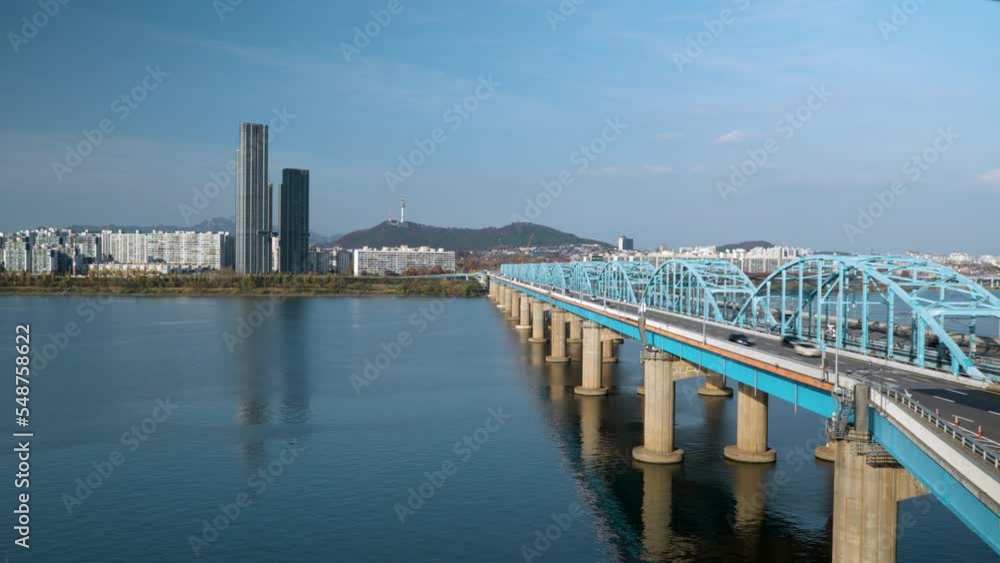 Aerial Time Lapse of Cars Traffic Driving on Dongjak Bridge Crossing Over Han River, distant view of N Seoul Tower in Skyline, South Korea Aerial Time Lapse of Cars Traffic Driving on Dongjak Bridge Crossing Over Han River, distant view of N Seoul Tower in Skyline, South Korea