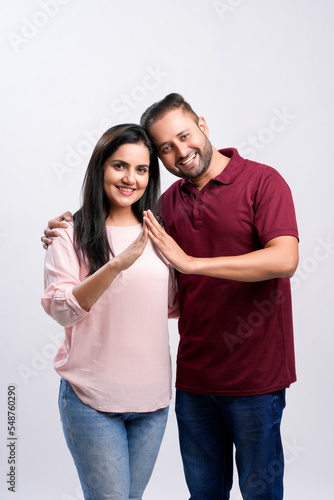 Indian couple making home symbol with hand on white background.