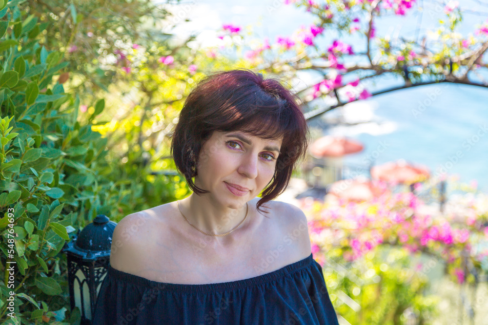 Portrait of a brunette woman 40-44 years old in a black dress with bare shoulders. Portrait of a brunette woman 40-44 years old in a black dress with bare shoulders.