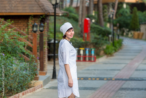Portrait of female doctor white coat and headdress outdoors.