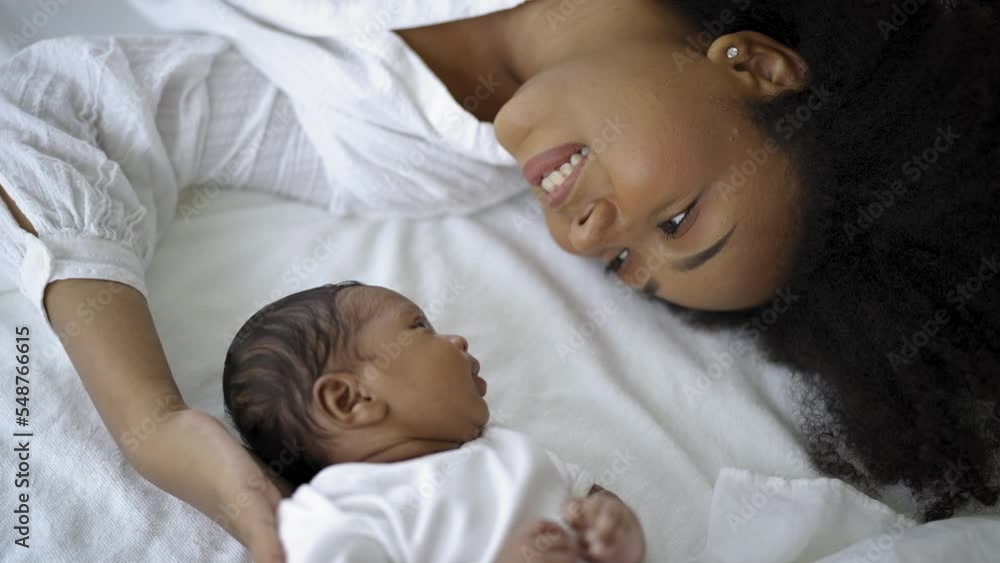 Closeup portrait of beautiful young African American mother day girl kiss healthy newborn baby sleep in bed flat lay copy space. Healthcare medical love black woman lifestyle mother's day. Closeup portrait of beautiful young African American mother day girl kiss healthy newborn baby sleep in bed flat lay copy space. Healthcare medical love black woman lifestyle mother's day.