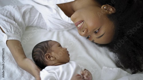 Closeup portrait of beautiful young African American mother day girl kiss healthy newborn baby sleep in bed flat lay copy space. Healthcare medical love black woman lifestyle mother's day.