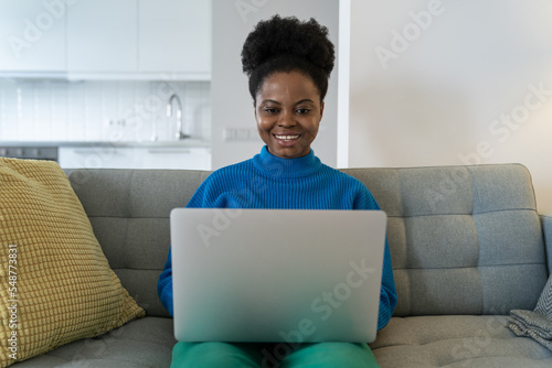 Fotobehang Successful African American woman freelancer smiling working from home doing order using laptop