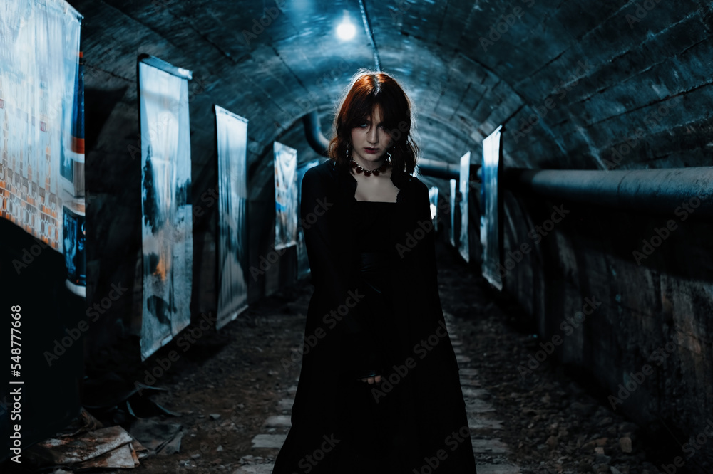 Young woman model posing in black dress in dark tunnel underground Young woman model posing in black dress in dark tunnel underground
