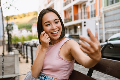 Young beautiful smiling happy asian girl taking selfie on phone photo