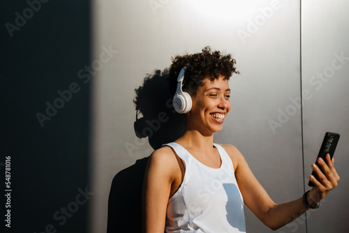 Black woman in headphones using cellphone and smiling