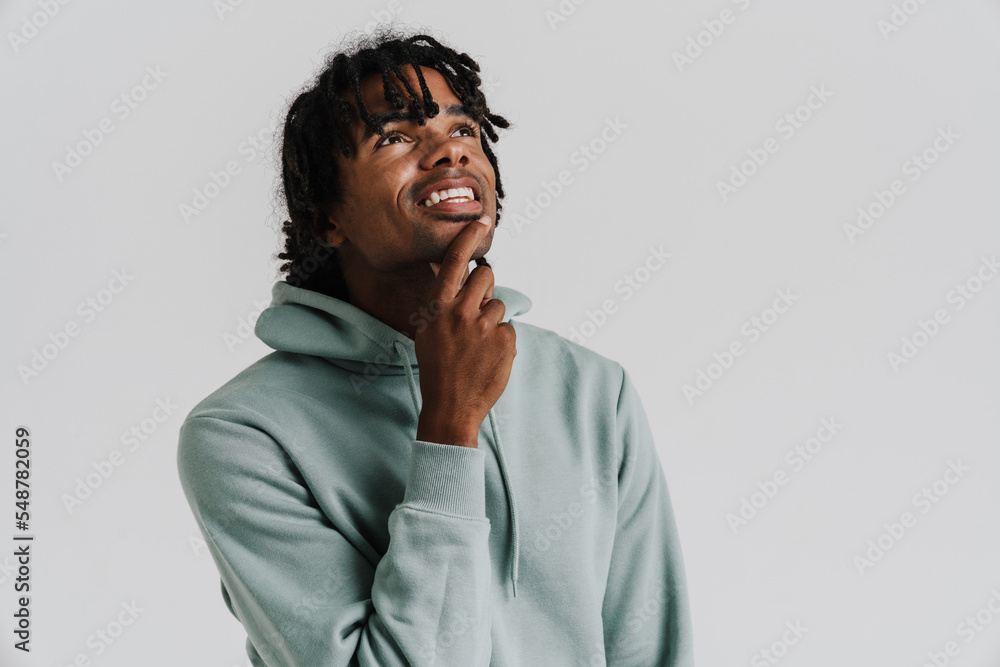 Young man dressed in hoodie touching his and chin looking upward Young man dressed in hoodie touching his and chin looking upward