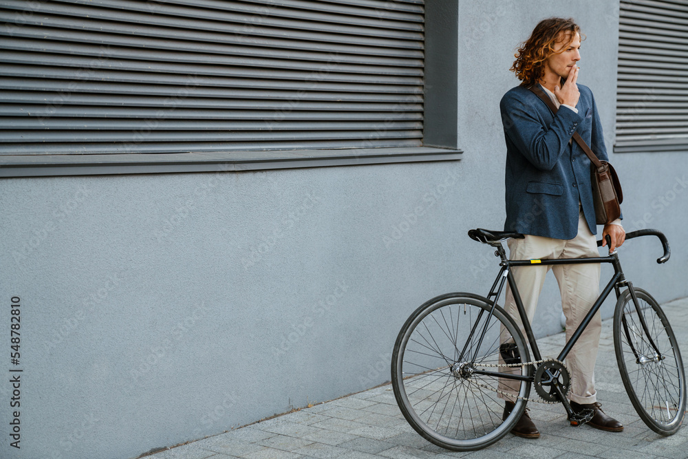 Young man smoking cigarette while standing with bicycle Young man smoking cigarette while standing with bicycle