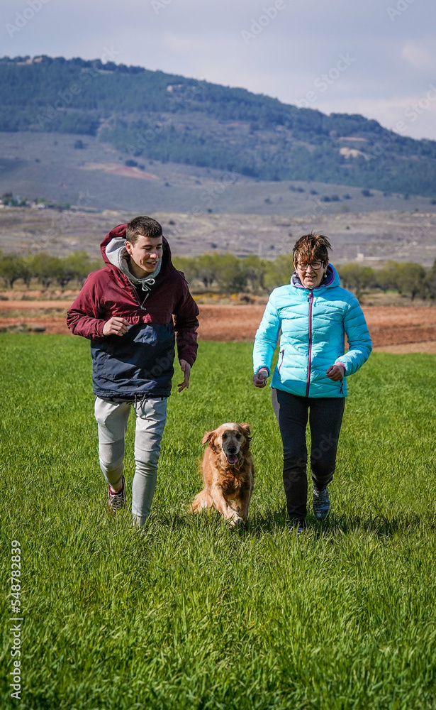 Family running with their pets in winter and happily enjoying the freedom of the mountains and nature.