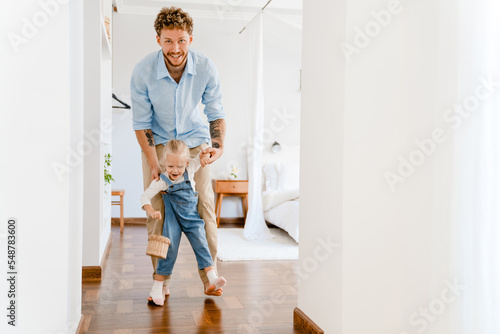 Young white father smiling and walking with his little daughter at home