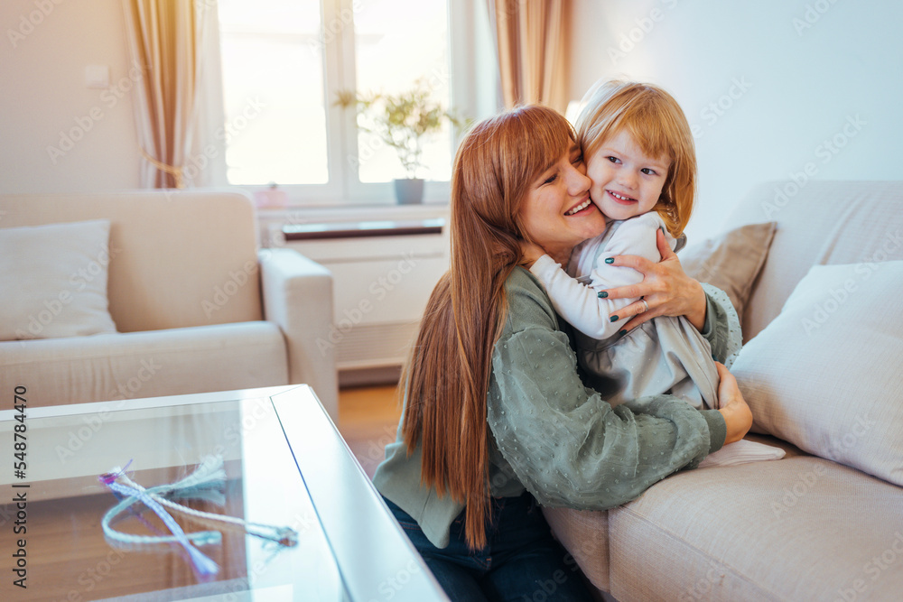 Happy mother and daughter playing and embracing at home. Happy mom carrying her little daughter. Mother and daughther happy together. Togetherness Concept. Daughter hugging her mum