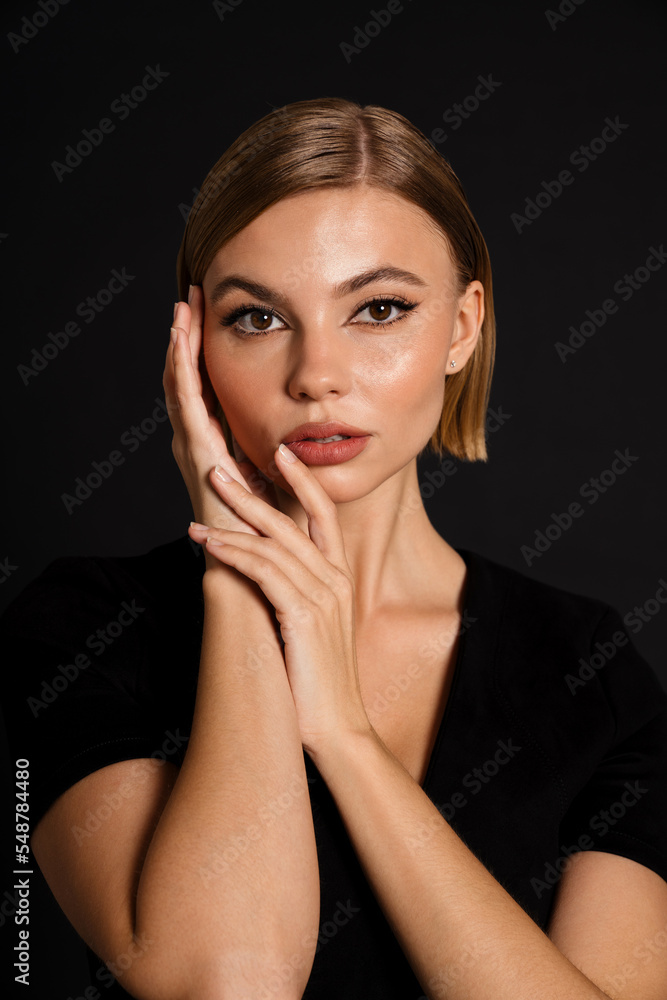 Young woman posing with folded hands on her cheek isolated over black background Young woman posing with folded hands on her cheek isolated over black background