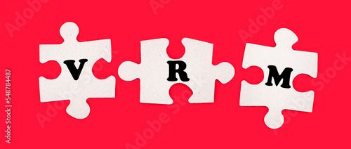 Three white jigsaw puzzles with the text VRM Vendor Relationship Management on a bright red background. photo
