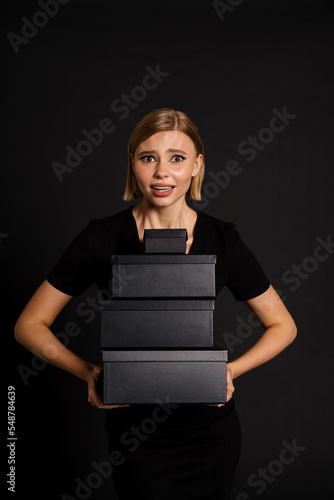 Confused woman holding gift boxes isolated over black background photo