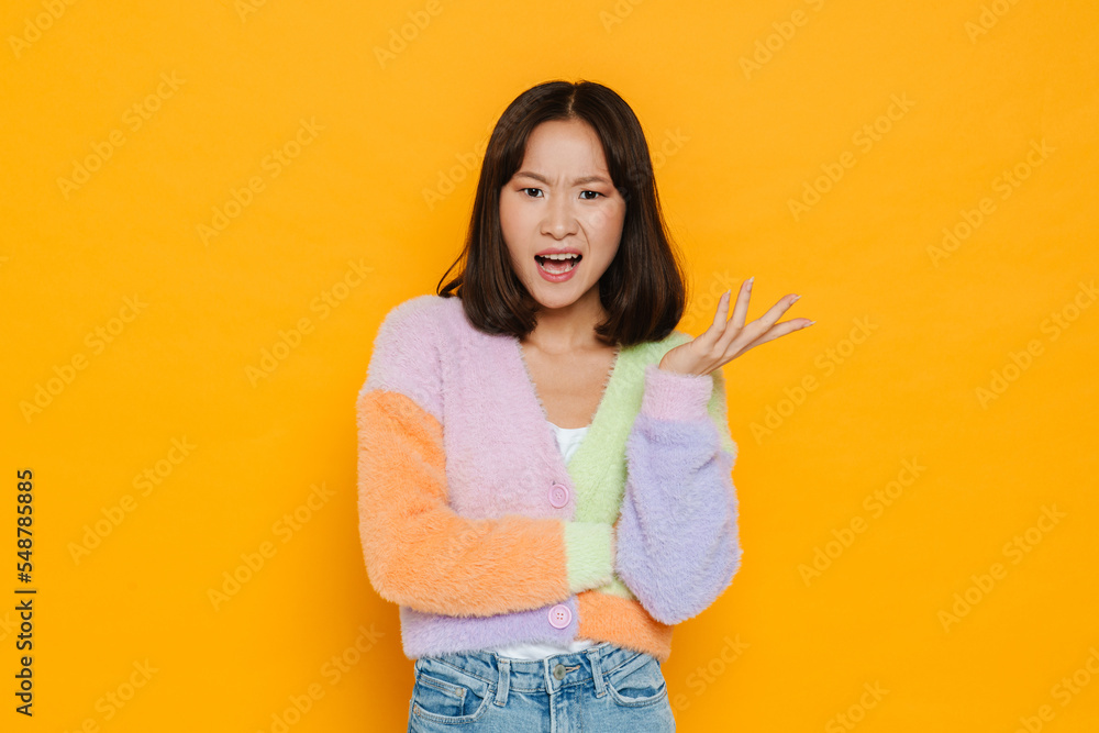 Confused asian girl posing isolated over yellow background Confused asian girl posing isolated over yellow background