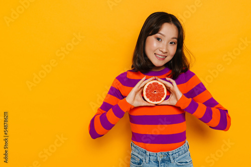 Asian brunette woman smiling and holding grapefruit © Drobot Dean