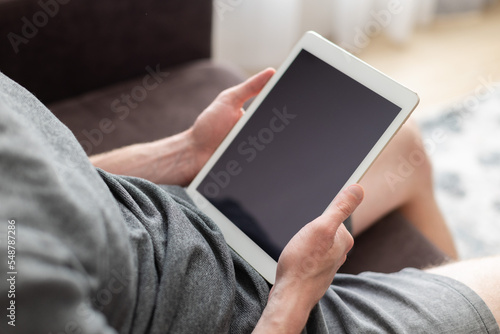 Man sitting on a couch with a tablet in his hands. Mockup.