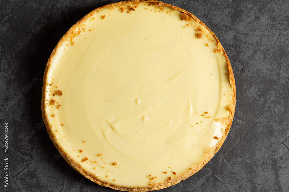 Homemade classic cheesecake on a dark background. Making a delicious cake at home