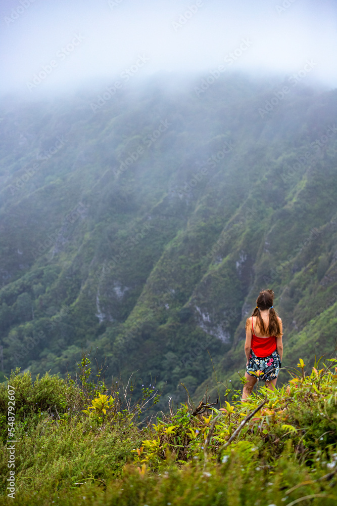 Fototapeta premium girl in pigtails stands at the top of the kuliouou ridge trail admiring the panorama of oahu, honolulu and the hawaiian mountains; hiking in the mountains in hawaii, holiday in hawaii