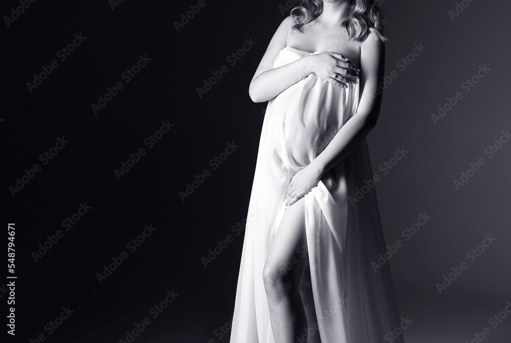 pregnant woman in white dress on a grey background, studio pregnancy shoot