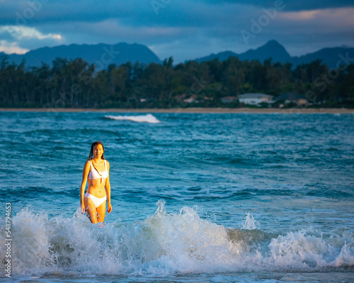 beautiful girl in a white bikini swims in the ocean on a paradise beach on oahu in the hawaii islands during sunset, holiday in hawaii, relax on the beach on oahu © Jakub