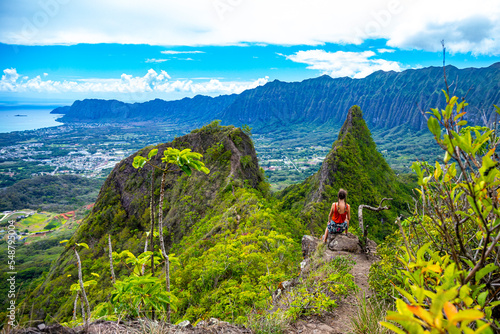 hiker girl stands at the top of olomana ridge trail admiring the panorama of oahu and hawaii mountains; famous three peaks on oahu, dangerous hiking on hawaii mountains, hawaii holidays photo