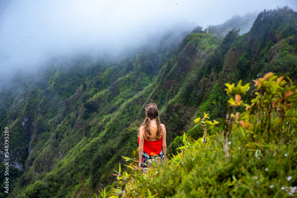 Naklejka premium girl in pigtails stands at the top of the kuliouou ridge trail admiring the panorama of oahu, honolulu and the hawaiian mountains; hiking in the mountains in hawaii, holiday in hawaii