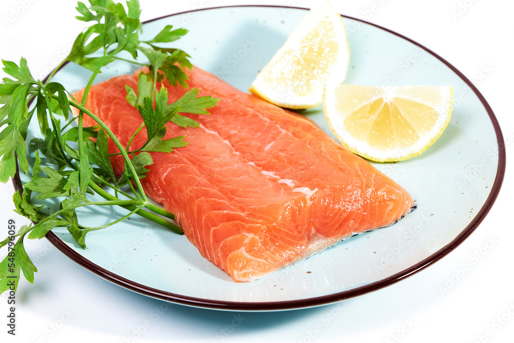 Salmon, fresh raw fish fillets together with parsley and lemon on a plate Salmon, fresh raw fish fillets together with parsley and lemon on a plate