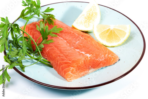 Salmon, fresh raw fish fillets together with parsley and lemon on a plate