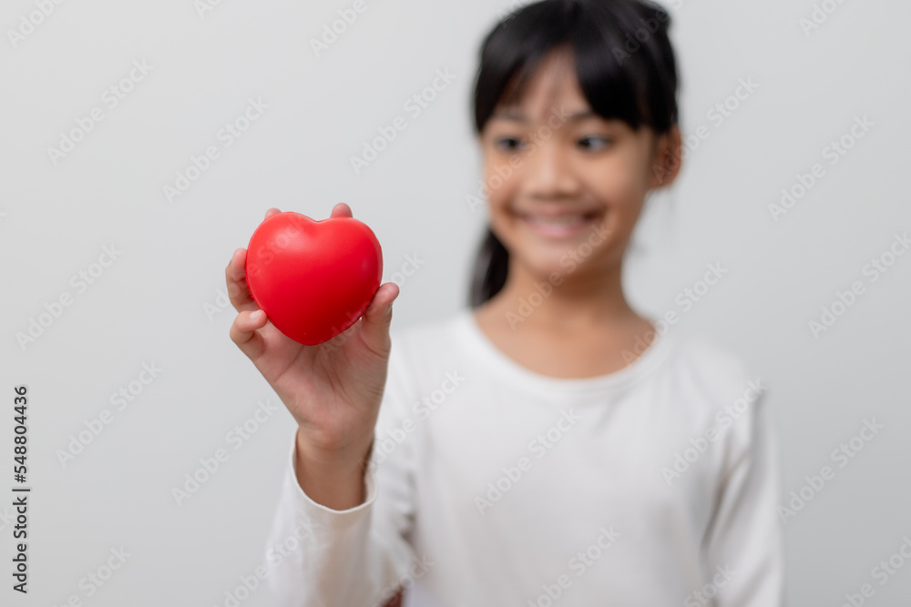 Portrait of Asian little girl child holding red heart sign on white background Portrait of Asian little girl child holding red heart sign on white background