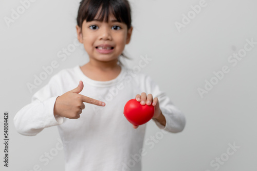 Portrait of Asian little girl child holding red heart sign on white background
