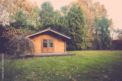 Beautiful forest hut for holidays in the forest. Garden shed with yellow leaves and trees in late autumn. Autumn mood in the country. garden maintenance