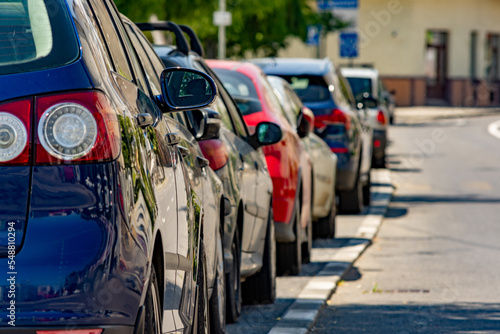 Close up to a row of parked cars on the side of a street in a residential or urban area