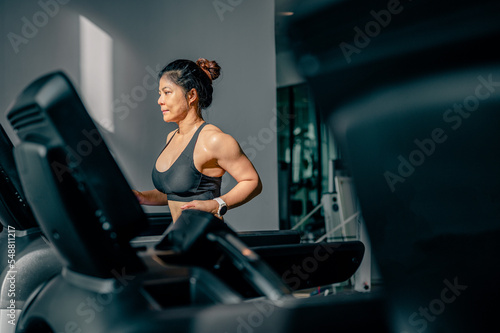 Side view of Asian women running or jogging on treadmill at gym.sport indoor burn weight and strong health.Fitness healthy lifestyle and workout concept.