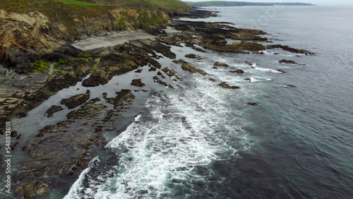 Tidal waves of the Atlantic Ocean. Rocks on the southern coast of the island of Ireland. White sea foam on the waves. Beautiful seaside landscape. Aerial photo.