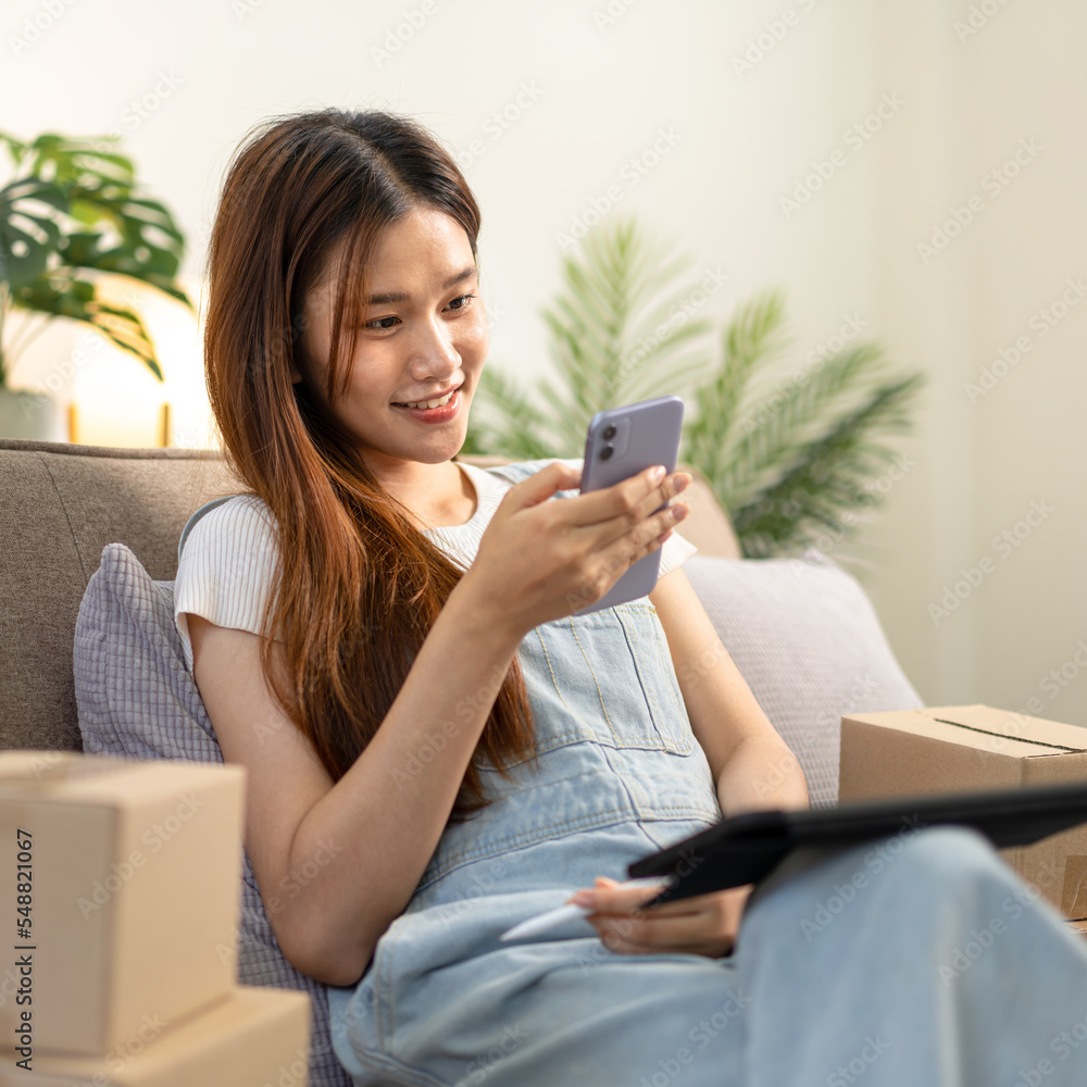 Young entrepreneur is checking online orders on smartphone while sitting on comfortable the couch Young entrepreneur is checking online orders on smartphone while sitting on comfortable the couch