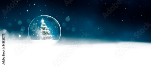 Schneekugel mit Schneeflocken und Weihnachtsbaum im Schnee