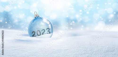 Durchsichtige Weihnachtskugel aus Glas  im Schnee mit Jahreszahl 2023