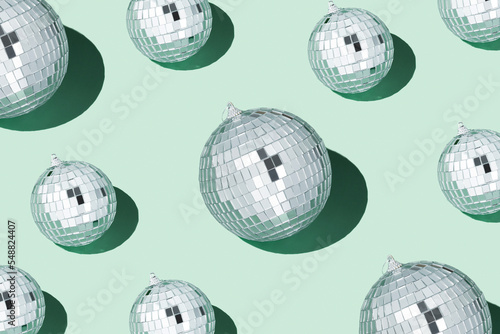 Fototapeta Naklejka Na Ścianę i Meble -  Shiny silver disco balls over green background. Creative Christmas pattern. 90s retro party time concept. Xmas holiday background. Top view. Flat lay.