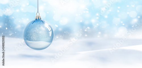 Fototapet Durchsichtige Weihnachtskugel hängend vor unscharfem Schneehintergrund