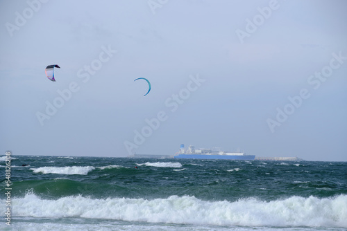 Kitesurfing  riding board waves during storm holding to flying kite.