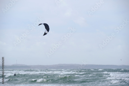 Kitesurfing, riding board waves during storm holding to flying kite.