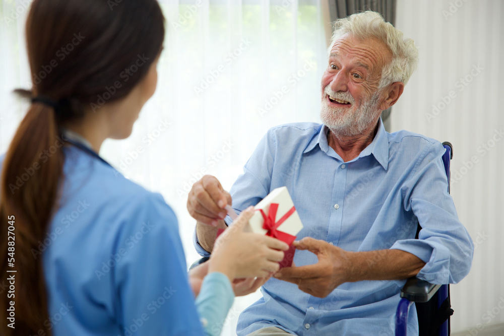 Obraz premium senior man taking a gift box from caregiver for happy birthday
