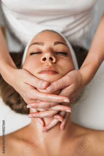 Body and neck massage in spa. Professional female beautician doctor with patient in wellness center. Cosmetologist working procedure to beautiful young woman in cosmetology cabinet or beauty parlor.
