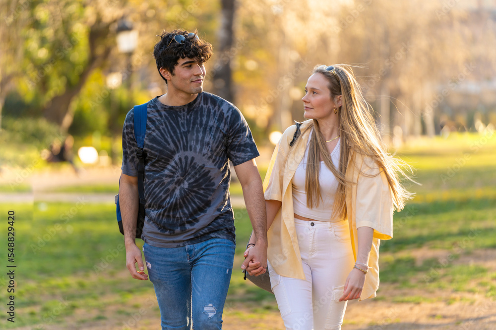 Young heterosexual couple walking in a park and looking each other Young heterosexual couple walking in a park and looking each other