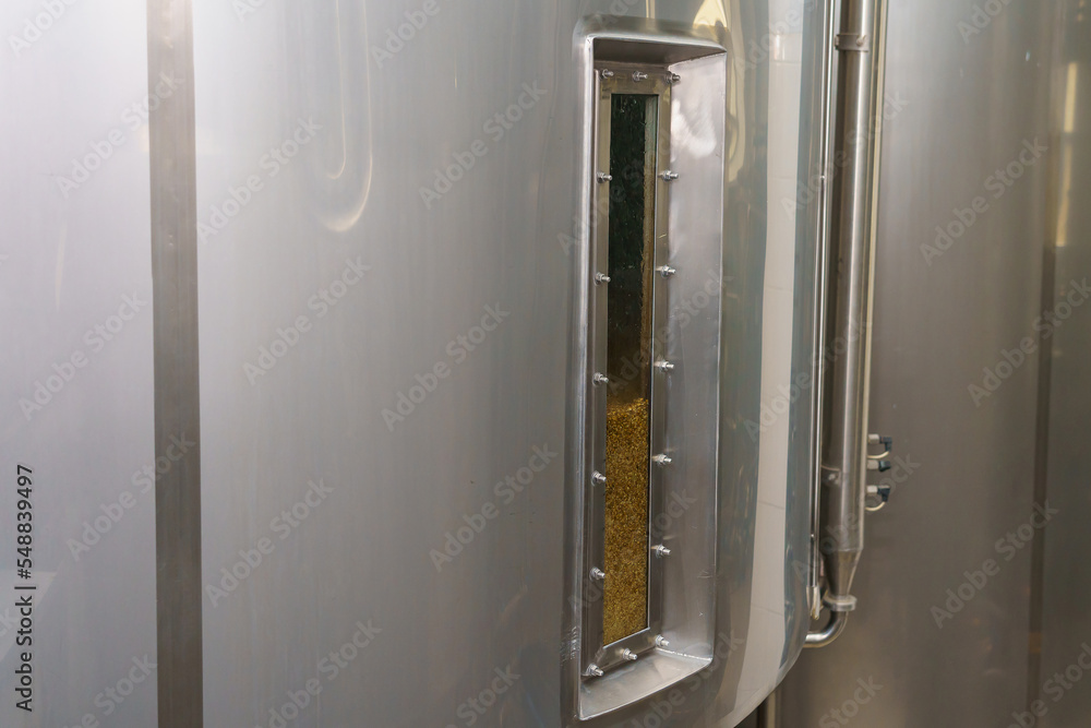 A stainless steel vat in the food industry at a brewery in the process of brewing beer. Background
