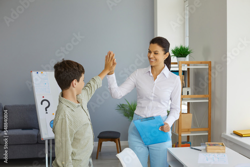 Woman professional psychologist high five with smile to teen boy her patient on the end of therapy session. Psychological help, psychotherapy, therapy, support for teens concept. Child psychologist. photo